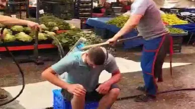 Sıcaktan bunalan pazarcıyı, esnaf arkadaşları hortumla yıkadı