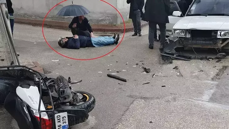 Kazada yaralanan motosikletlinin ıslanmaması için şemsiyeyle başında bekledi